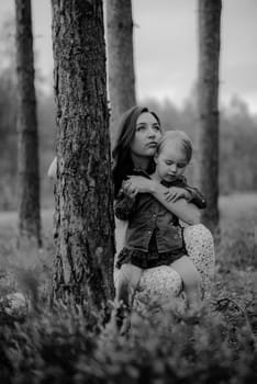 Happy mother and daughter in the park. Beauty nature scene with family outdoor lifestyle. Happy family resting together on the green grass, having fun outdoor. Happiness and harmony in family life.