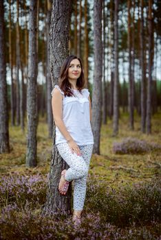 a photo of woman in the forest where the purple heather blooms. copy space. authentic image