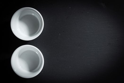 Two empty white ceramic dishes on a black stone board
