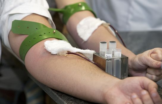   blood donation, hands with rubber tourniquet used in blood draw procedures.