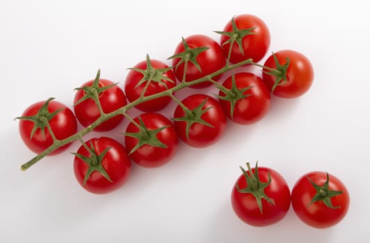 ripe cherry tomatoes on a branch, isolated on white.