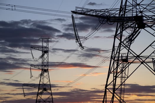 high voltage power pylons on against sunset sky