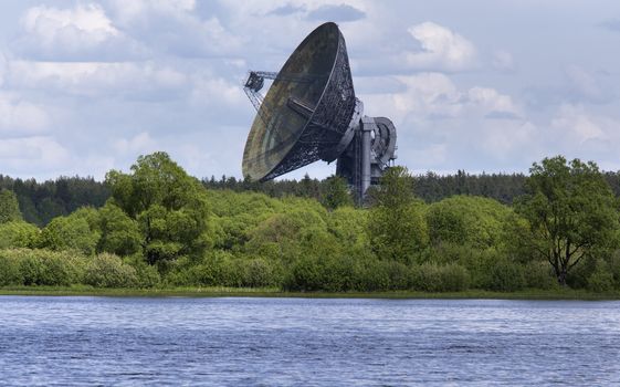 Huge satellite dish aimed at the sky, stands near river bank in Kaljazin, Russia.