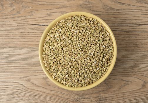 Natural fresh green buckwheat in ceramic bowl on wooden background. Top view.