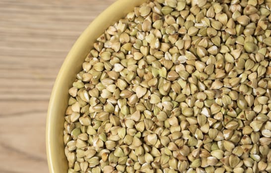 Natural fresh green buckwheat in ceramic bowl on wooden background. Top view.