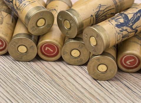Hunting cartridges of 12 gauge for shotgun on wooden background. Macro shot.