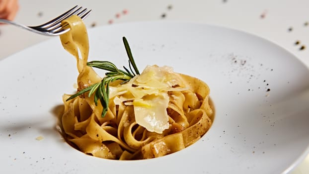 Close-up italian pasta plate with grated parmesan cheese and basil leaf.