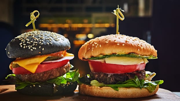 Set of homemade burgers in black and white buns with tomato, lettuce, cheese, onion on wood serving board over dark table. Rustic style. Homemade fast food