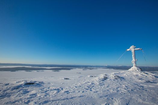 The cross on a snow covered mountain with panoramic view on Kandalaksha , ski resort