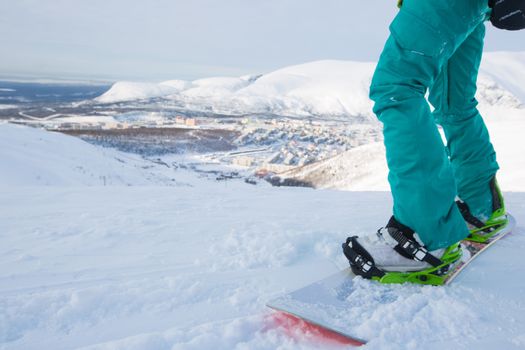 Kirovsk, Russia - Snowboarder on piste in high mountains on ski slope. Rear view. Winter snowboard and skiing concept. Khibiny Mountains, Kola Peninsula panoramic view in town