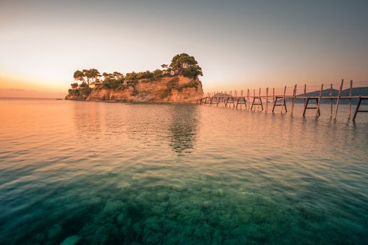 Beautiful sunrise, just before the storm rains. The famous Cameo island. A beautiful small island with wooden bridge and turquoise water. Zakynthos Greece.