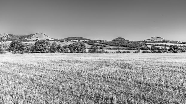 Landscape of Ceske Stredohori, aka Central Bohemian Highlands, with typical spiky hills of volcanic origin, Czech Republic. Black and white image.