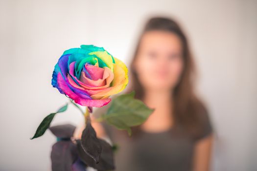 Young woman with rainbow rose. Bright background.