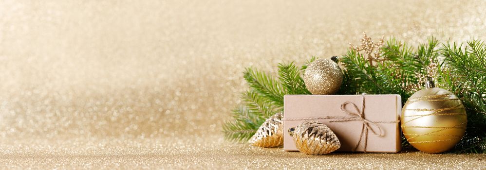 Christmas toys, decorations, present gift box wrapped in kraft paper on golden glitter background, copy space