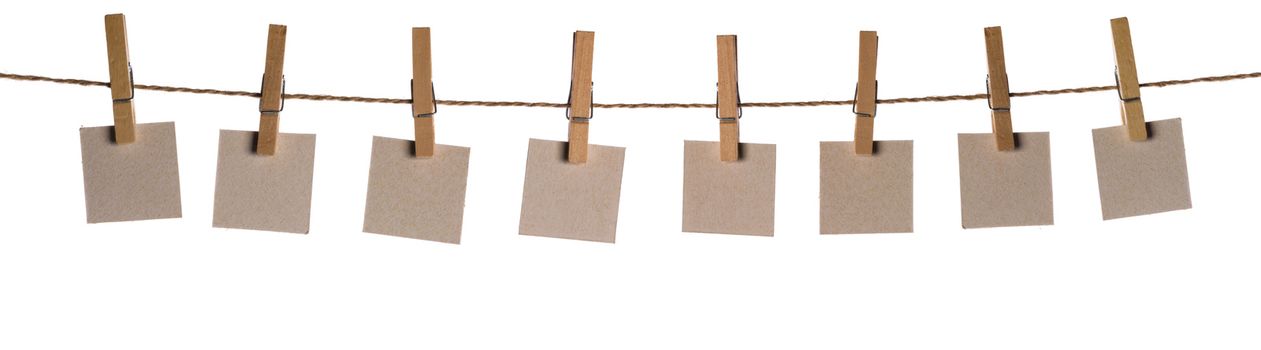 Set of eight blank paper notes held on a string with clothespins isolated on white background
