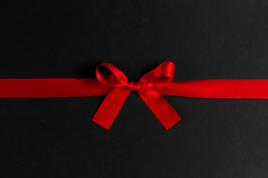 Shiny red satin ribbon and bow on black background. Holiday gift concept