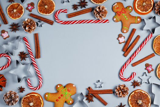 Christmas food frame. Gingerbread cookies, spices and decorations on blue background with copy space