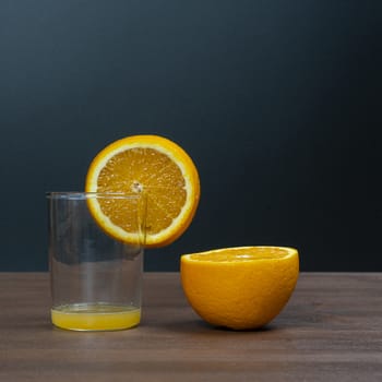 An orange fruit sliced and a glass on a wooden surface