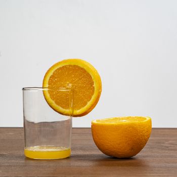 An orange fruit sliced and a glass on a wooden surface