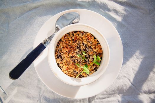 baked oat-blueberry crumble with mint in a white and blue plate on a rustic linen tablecloth. Save the space, top view. The concept of healthy proper nutrition for breakfast, vegetarianism