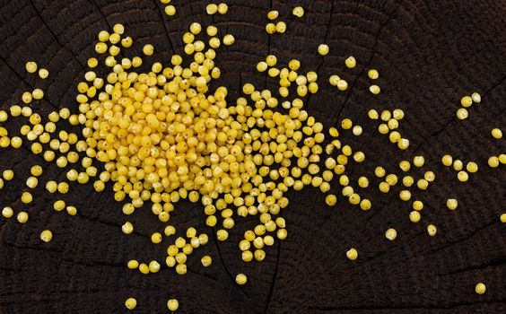 Heap of millet groats on black wooden background, top view
