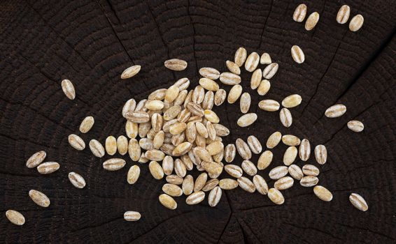 Heap of pearl barley on black wooden background, top view