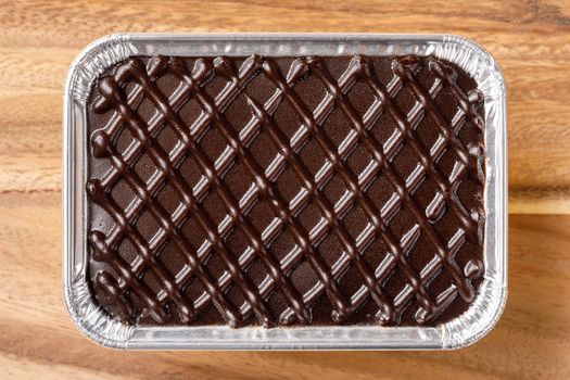 Chocolate cake in aluminium foil tray on wooden table or cutting board