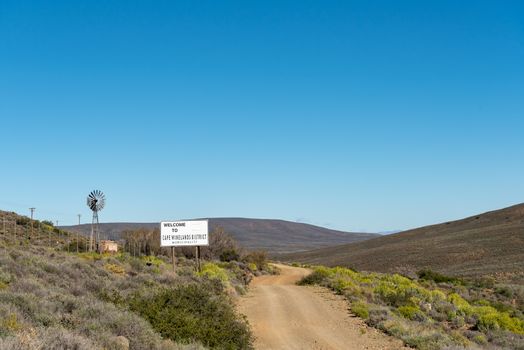 A landscape, with welcome sign, windmill and dam, on road R356 to Ceres in the Western Cape Province.
