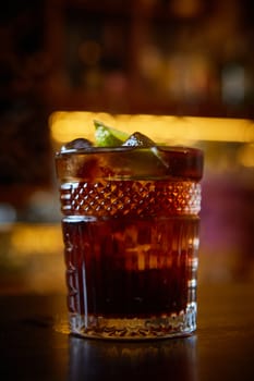 High angle view of a glass of Cuba Libre cocktail with rum, coke, lemon juice and ice cubes.