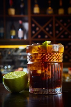 High angle view of a glass of Cuba Libre cocktail with rum, coke, lemon juice and ice cubes.