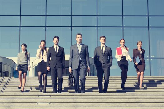 Group of business people walking down stairs in front of office building