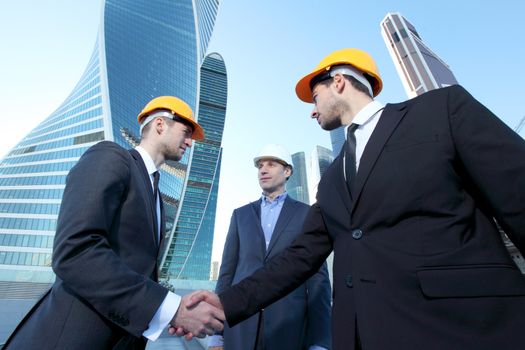 Investor and contractor shaking hands, view from below