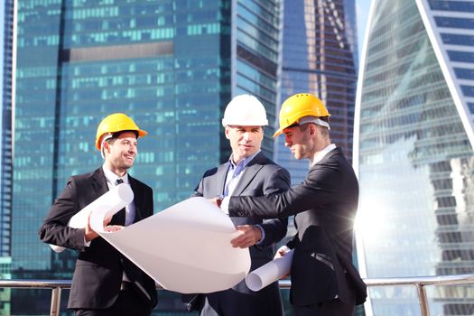 Architects with blueprint at skyscrapers background