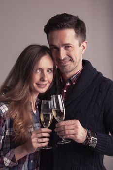 Happy mature couple in casual clothes embracing and clinking glasses of champagne