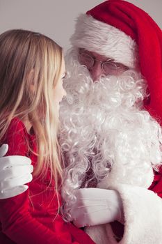 Little girl sitting on santa claus knees and talking to him