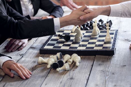 Businessman play chess and shake hands after the game