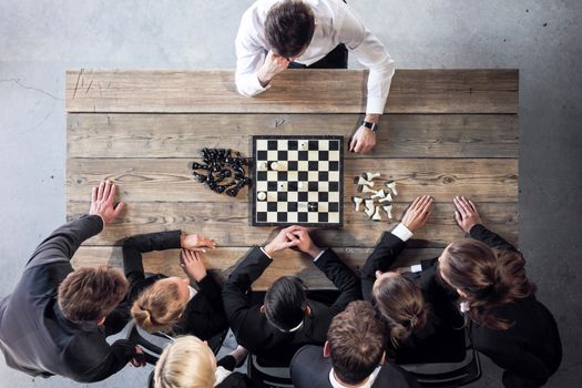 Business people playing chess, team of workers losing, leader is winning