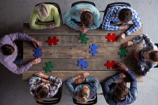 Business people and puzzle on wooden table, teamwork concept