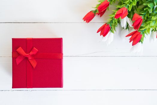 Red gift box and flower on white wooden background with copy space, valentine day concept