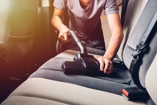 Worker man cleaning dust interior vacuum inside car