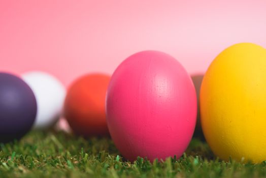 Colorful Easter eggs clean on grass and pink background, easter day concept