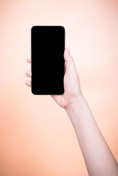 Female holding mobile smartphone plus blank screen on orange color background