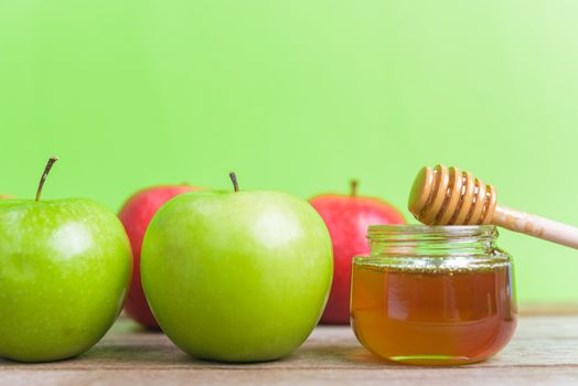 Jewish holiday, Apple Rosh Hashanah dessert, on the photo have honey in jar have red apples and green apples on wooden with green background