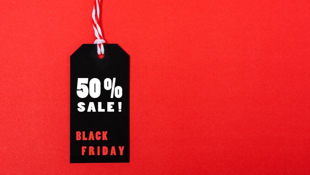 Online shopping, Promotion Black Friday Sale 50% text on black tag on red background.