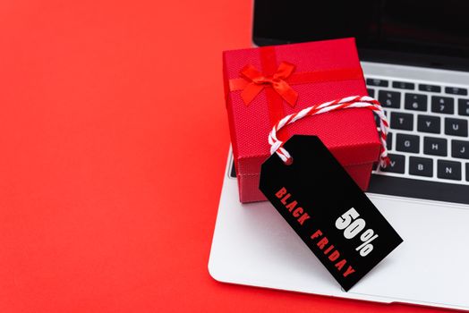 Online shopping, Promotion Black Friday Sale text on black tag with computer laptop and gift box on red background.