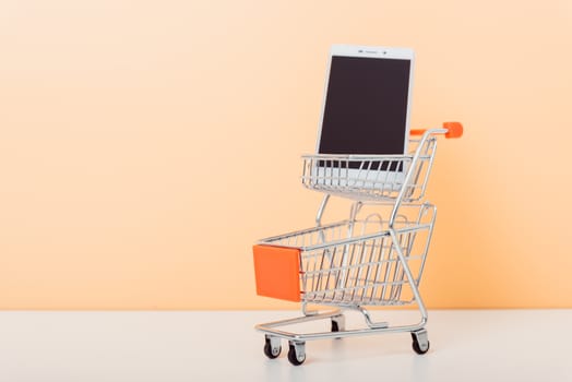 Mock up shoppong online cart and smartphone on desk table office soft yellow wall