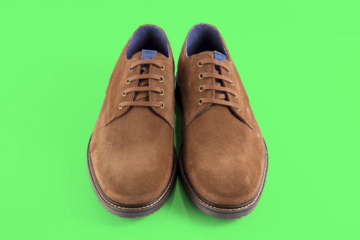 Pair of brown shoes on green background, isolated product.
