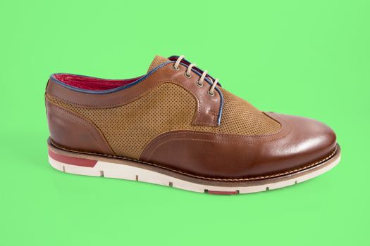 Male brown shoes on green background, isolated product.