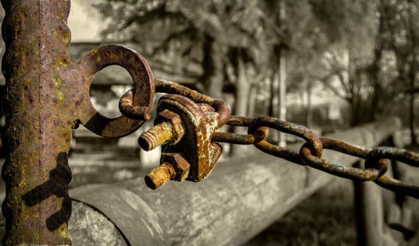 Detail of a rusty chain and a padlock and corroded by time in a situation with low very bleak and gloomy lighting.