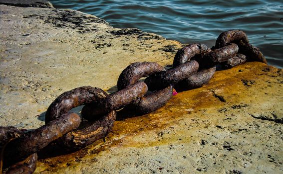 Detail of an old rusty chain and eroded by time and salt in a pier of the magical city of Venice.